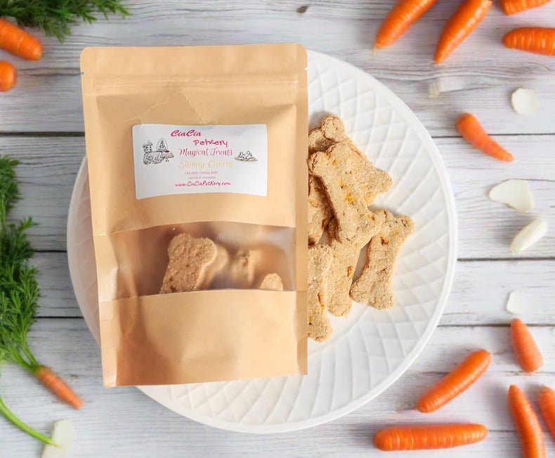 A brown resealable pouch labeled "CiaCia Perkery Magical Treats - Skinny Carrot" is placed on a white plate alongside bone-shaped dog treats. The setup is decorated with fresh carrots, carrot greens, and white wooden background.